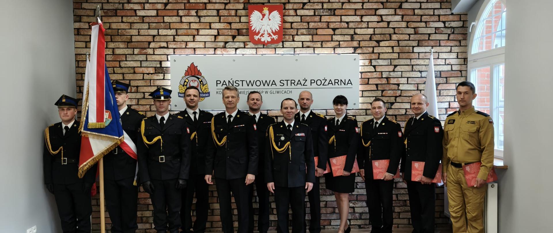 Zdjęcie grupowe strażaków: Komendant Miejski PSP, dowódcy, wyróżnieni, strażak który złożył ślubowanie, poczet sztandarowy.