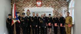 Zdjęcie grupowe strażaków: Komendant Miejski PSP, dowódcy, wyróżnieni, strażak który złożył ślubowanie, poczet sztandarowy.