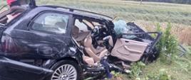 Rozbity samochód osobowy z wyciętym słupkiem i tylnymi drzwiami znajduje się w rowie. 
