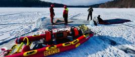 Strażacy nurkowie ćwiczą na zamarzniętych akwenie nurkowanie podlodowe, wykorzystując sprzęt nurkowy i do ratownictwa wodnego
