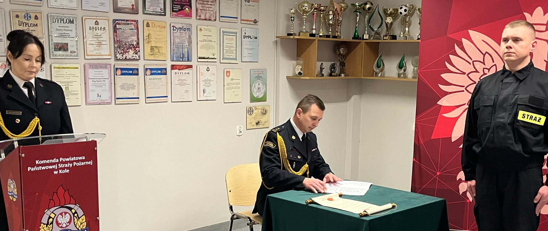 Zdjęcie przedstawia zastępcę komendanta powiatowego podpisującego akt ślubowania