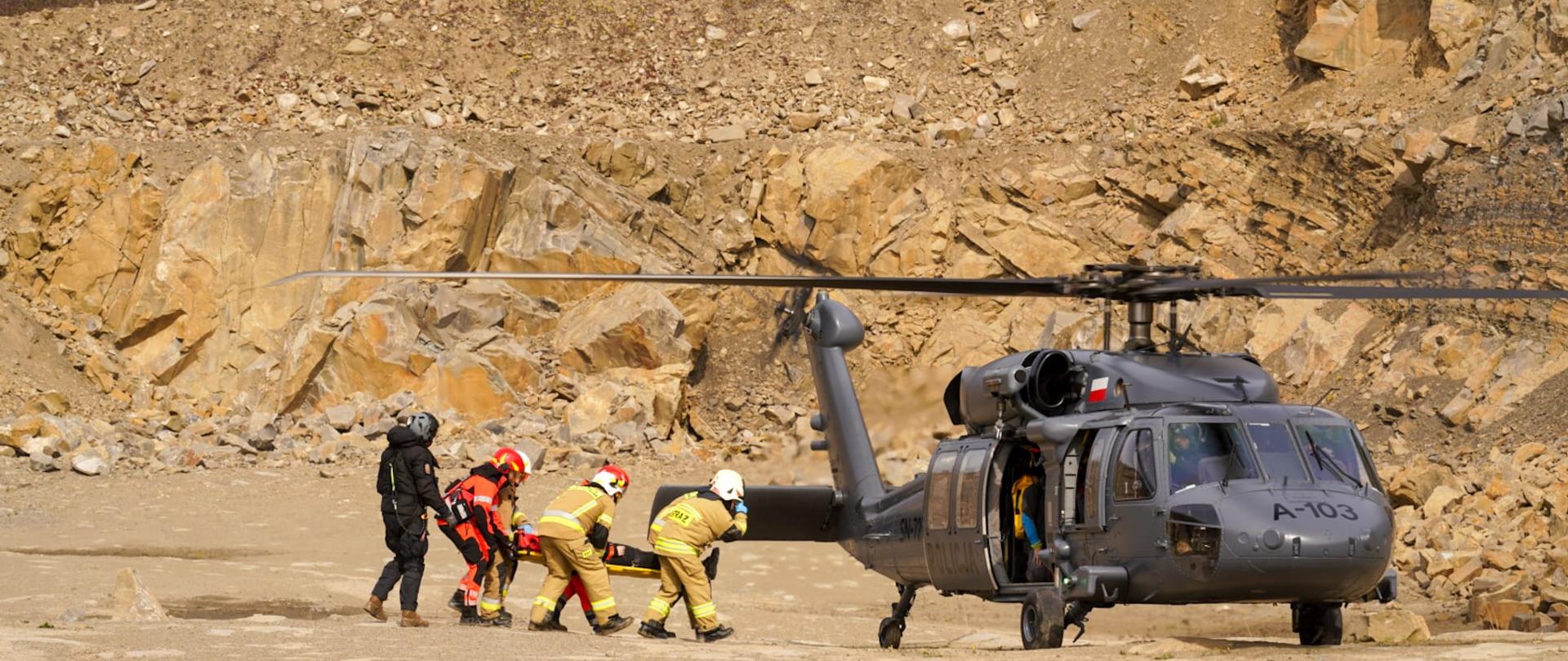 Poszkodowany w wypadku niesiony a noszach typu deska w celu ewakuacji do śmigłowca Policji i dalszej ewakuacji do punktu medycznego