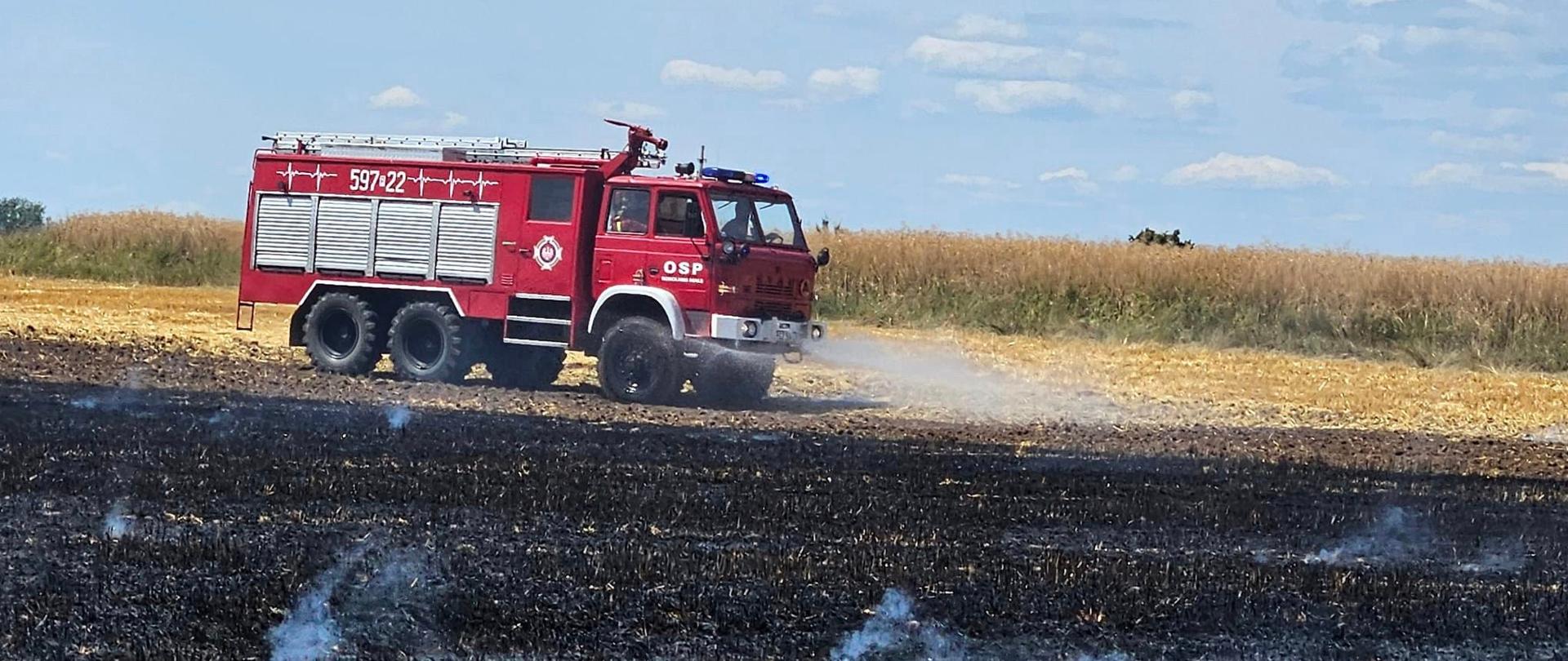 Samochód strażacki polewa wodą ściernisko
