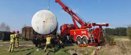 Warsztaty ratownicze grup specjalistycznych – dzień IV - wagon z cysterną wisi na dźwigu rotatora a strażacy próbują ustawić go na torach kolejowych