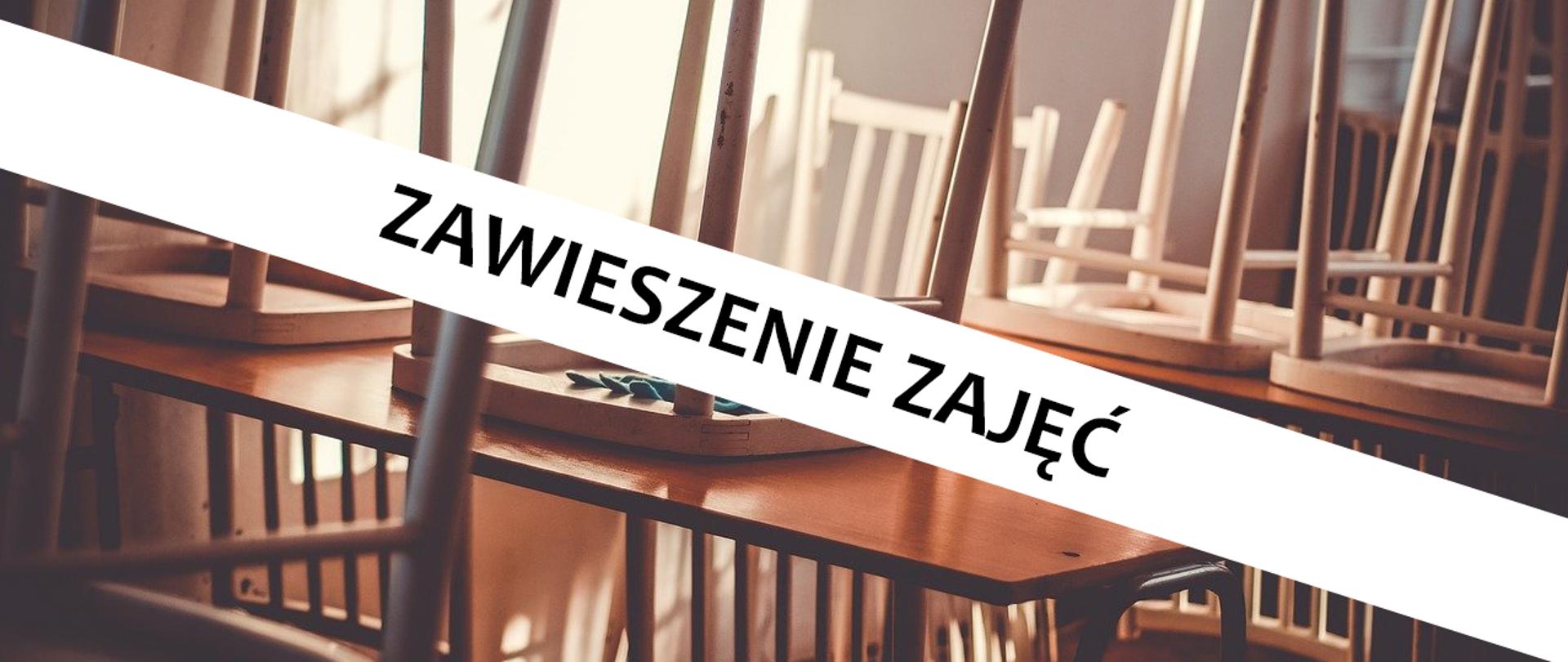 Klasa szkolna z krzesłami zawieszonymi na ławkach oraz napisem "zawieszenie zajęć".