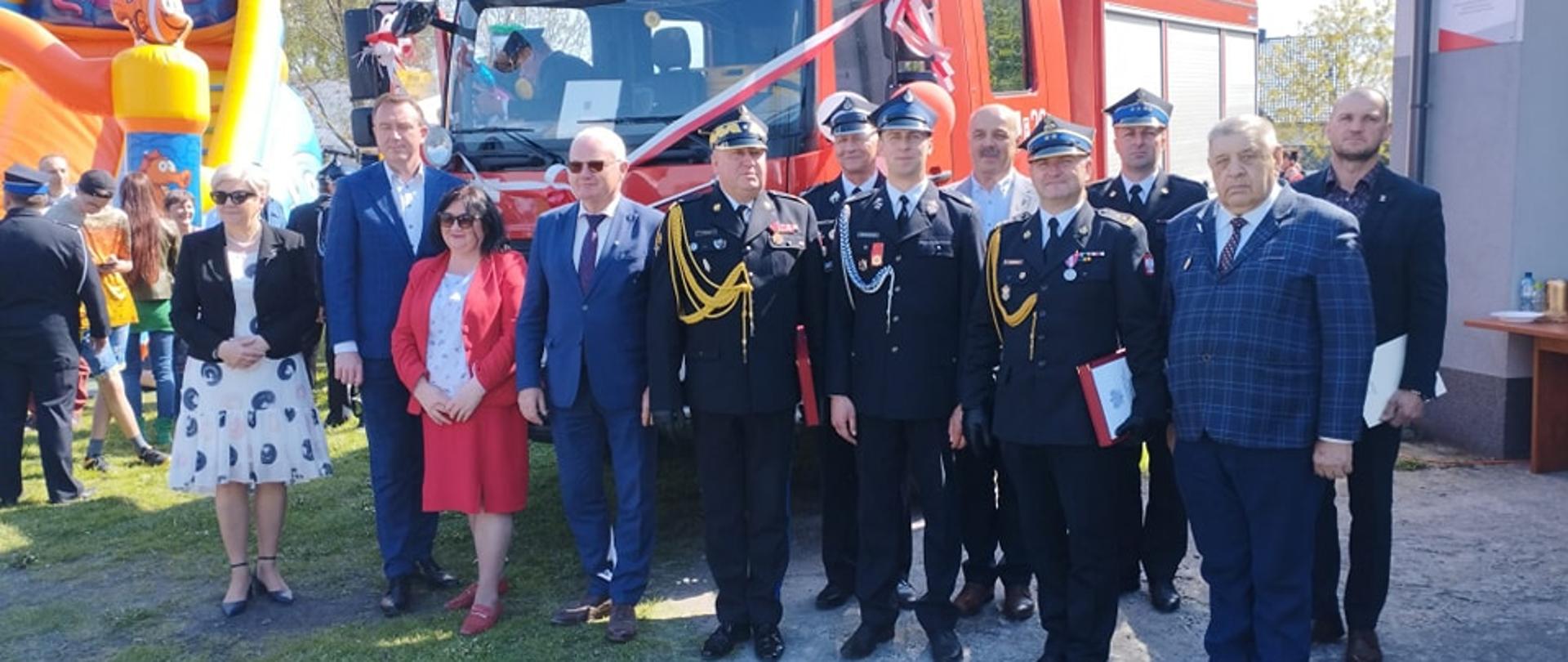 uczestnicy uroczystości strażacy druhowie politycy pozują do zdjęcia przed nowym samochodem pożarniczym