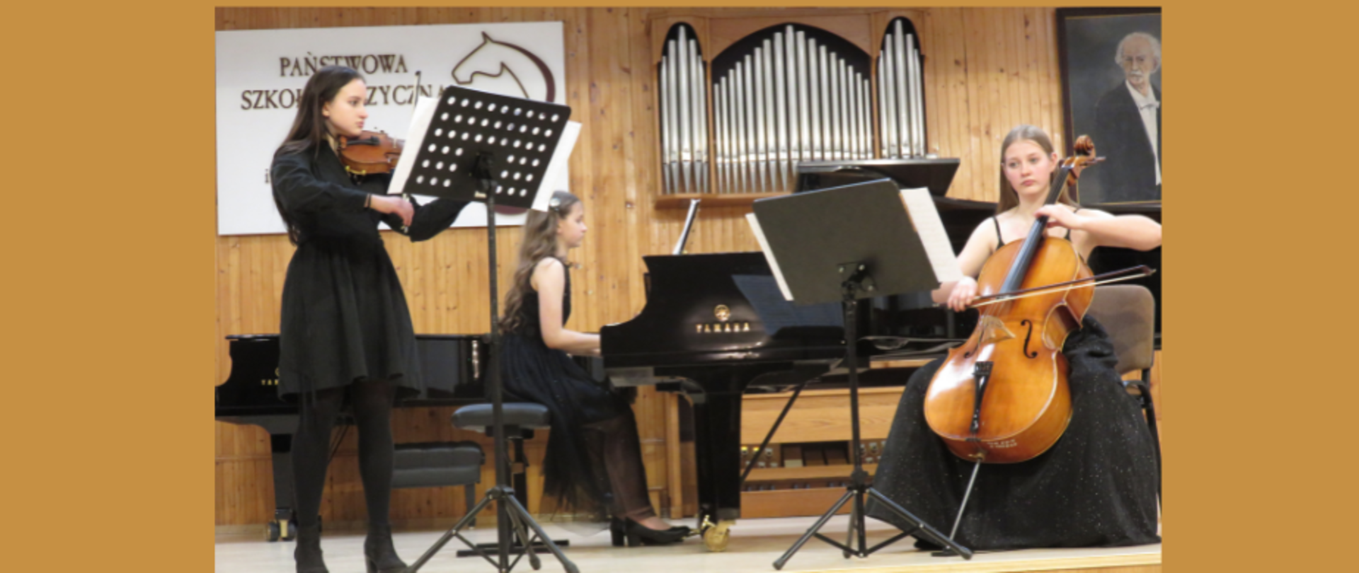 Trio fortepianowe w składzie : Martyna Guglas – skrzypce
Julia Lewandowska – wiolonczela
Antonina Waliszewska – fortepian
Uczennice w strojach wizytowych znajdują się na scenie PSM w Koninie