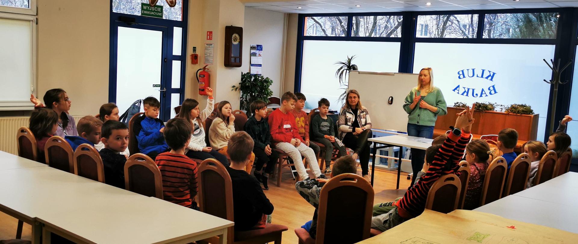 Dzieci siedzą w kręgu i słuchają prelegentki