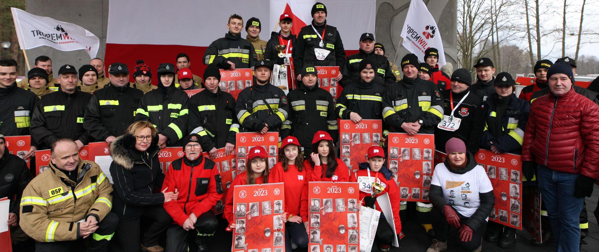 Laureaci biegu oraz osoby towarzyszące (młodzież orz dorośli w mundurach strażackich) w towarzystwie europosłanki Jadwigi Wiśniewskiej