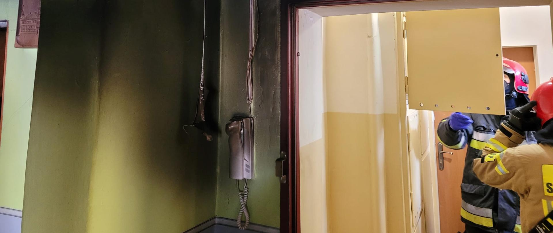 widok strażaków weryfikujących skrzynkę elektryczną