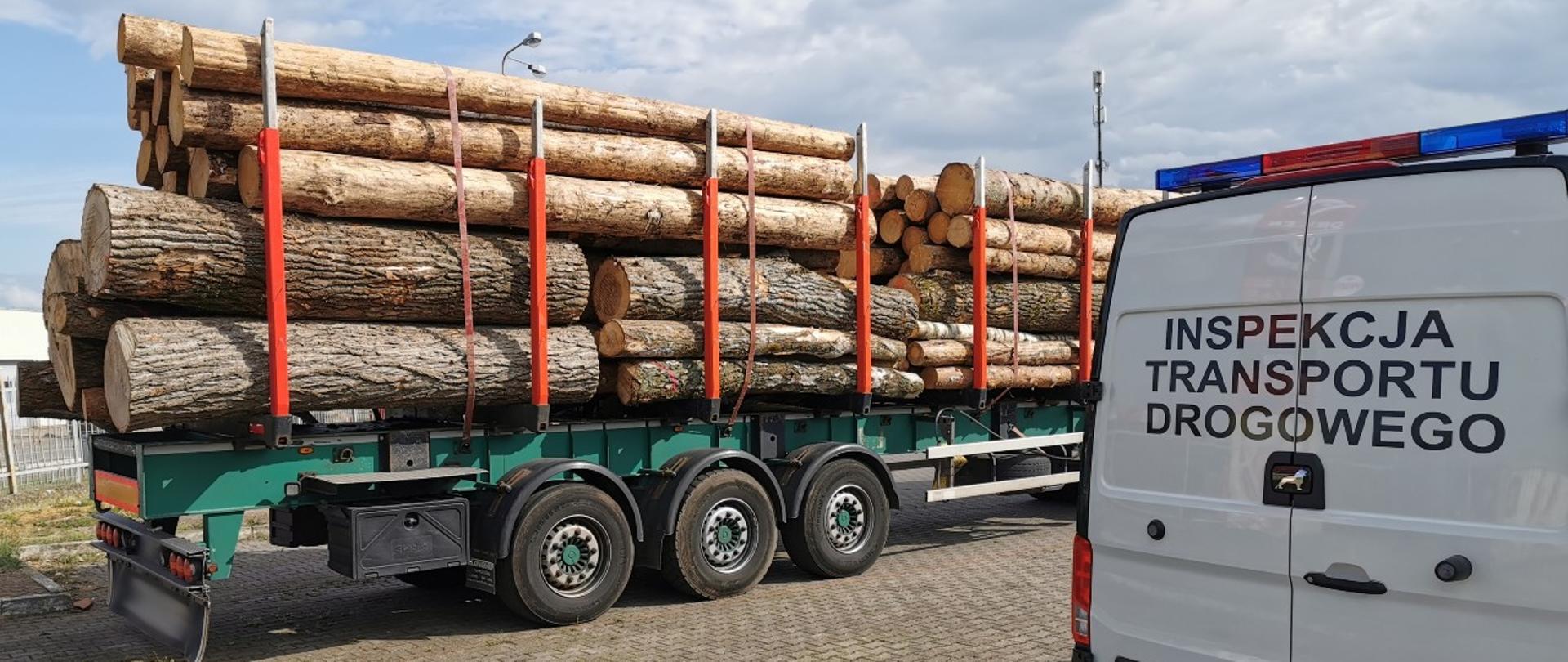 Zatrzymana do kontroli drogowej ciężarówka z ładunkiem drewna i radiowóz ITD. typu furgon.