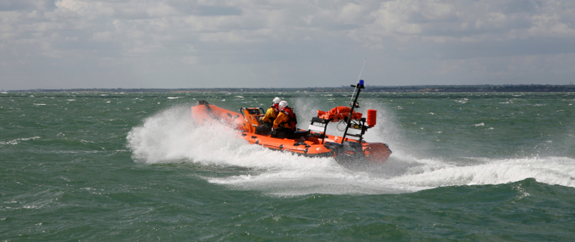 lodź motorowa na morzu, w niej ratownicy wodni w pomarańczowych kapokach
