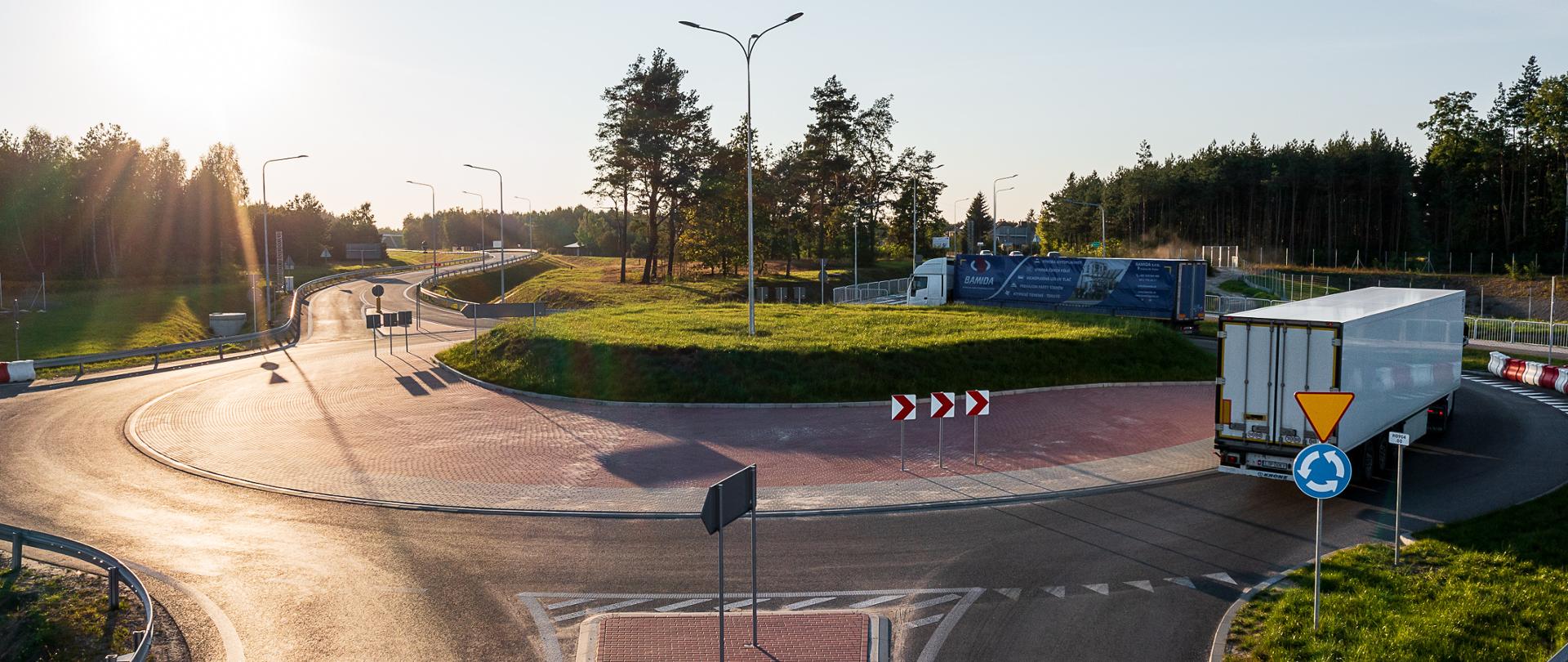 Widok na rondo na drodze krajowej nr 77 skrzyżowanie z S19, na rondzie dwa samochody, zachód słońca