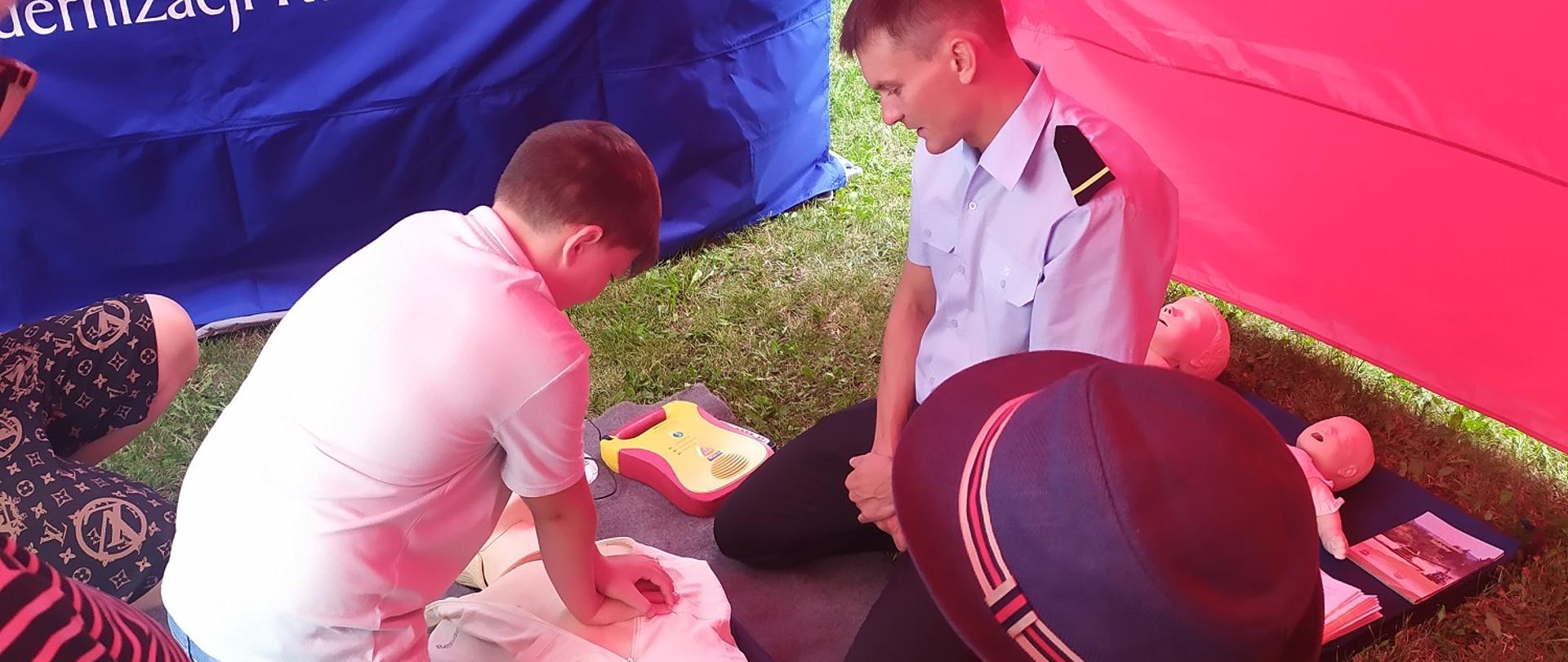 Zdjęcie przedstawia strażaka udzielania instruktażu udzielania pierwszej pomocy.