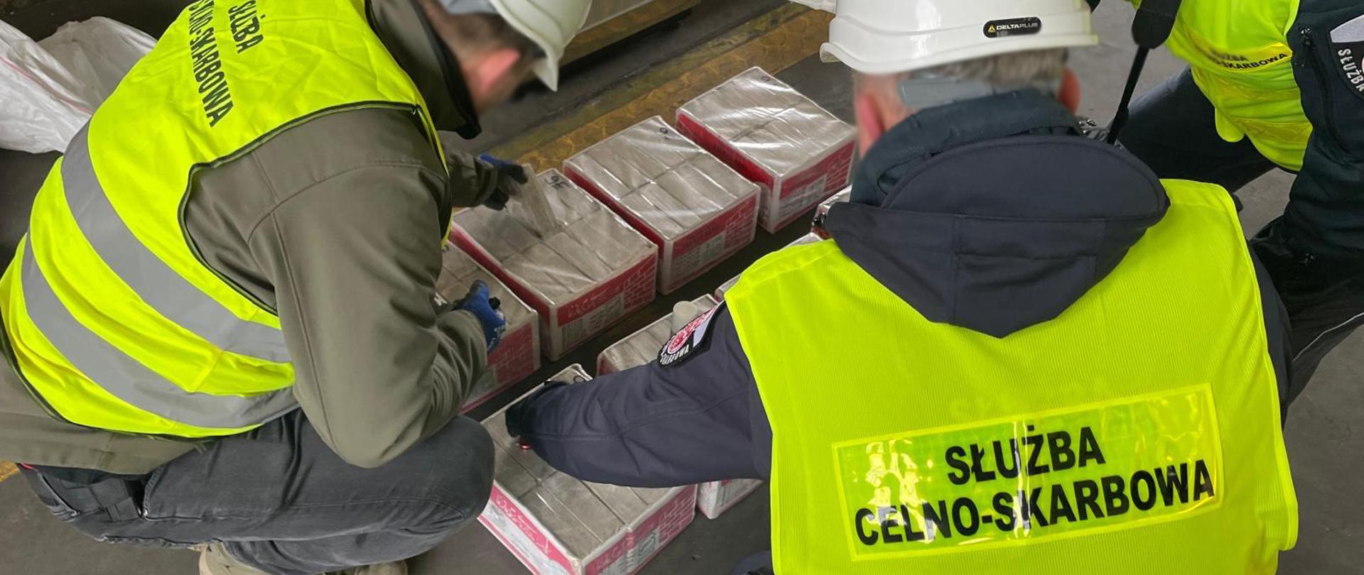 Funkcjonariusze Służby Celno-Skarbowej przeglądają kartony z ozdobnymi cegłami.