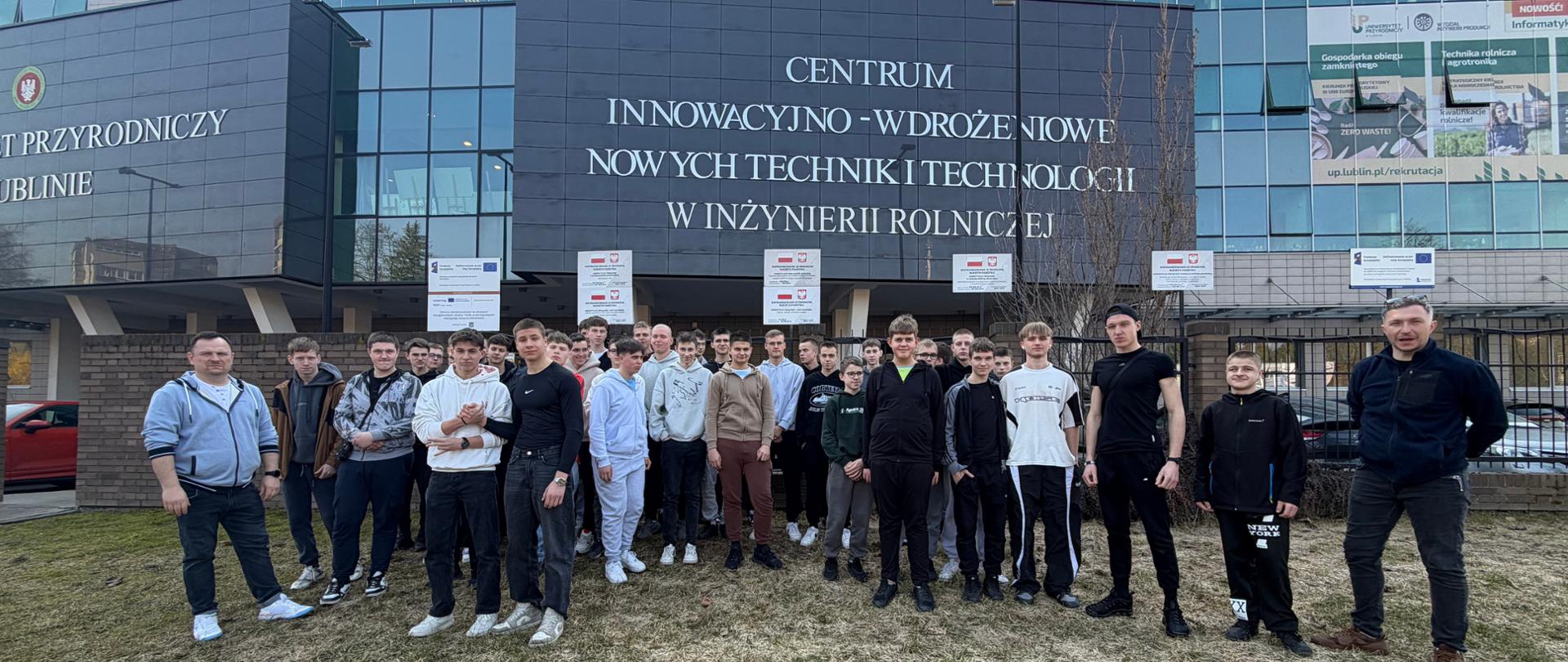 Zdjęcie pamiątkowe uczniów ZSCKR i nauczyciele przed budynkiem uczelni 