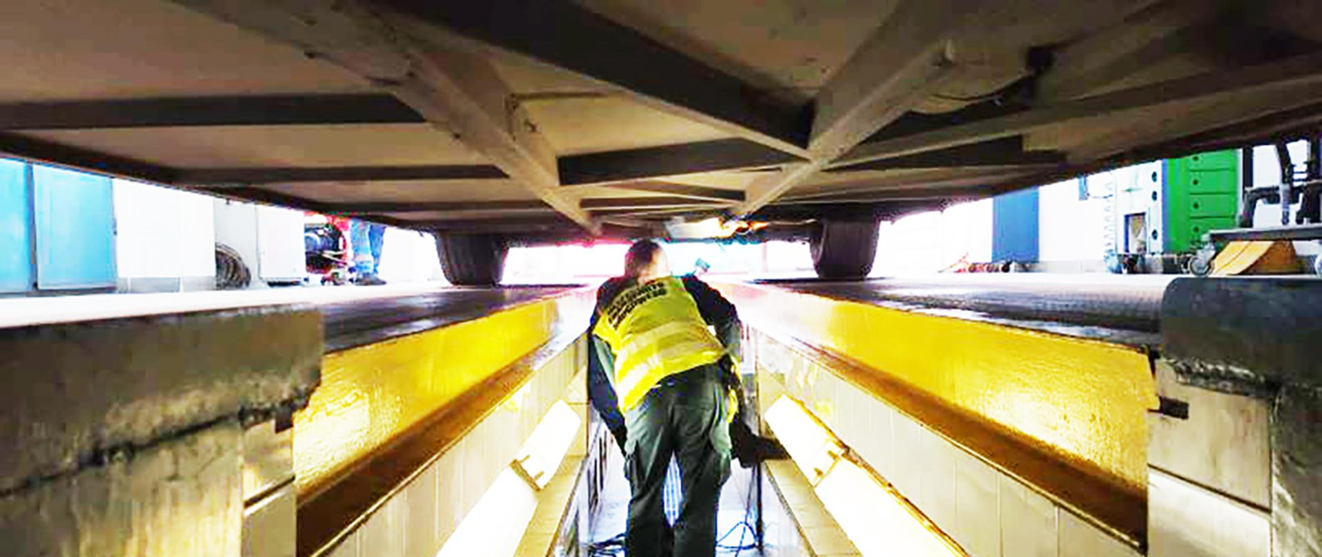 Sprawdzanie stanu podwozia. Inspektor ITD ogląda podwozie autobusu. Kontrola pojazdu w stacji kontroli pojazdów.