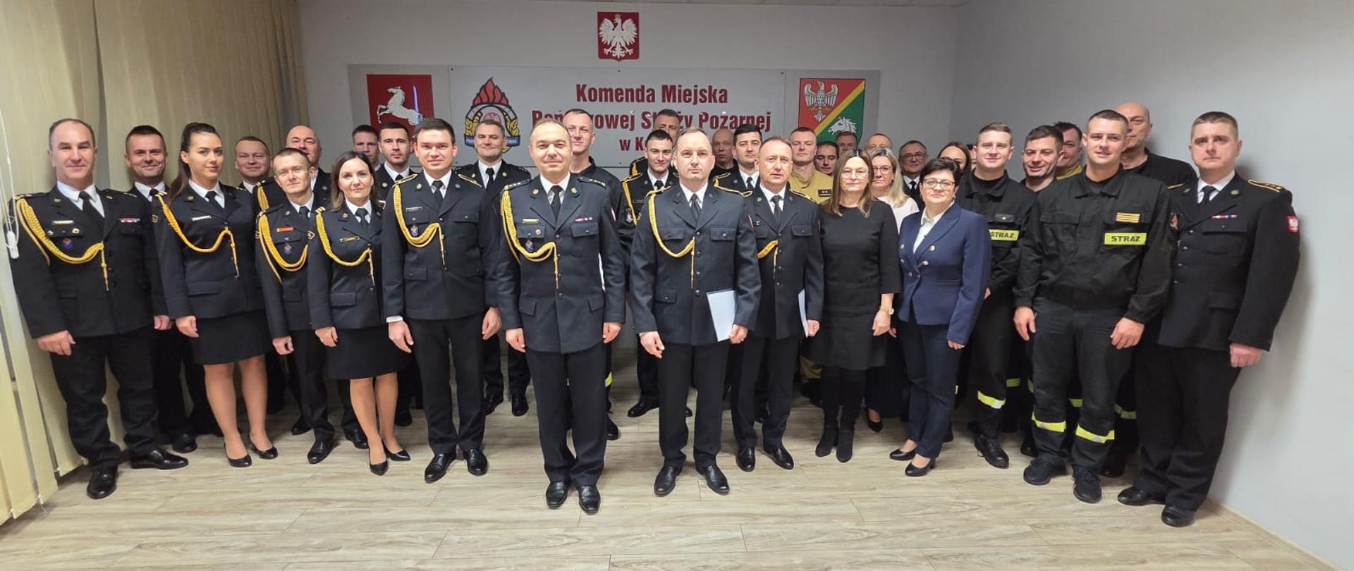 Strażacy stoją w świetlicy podczas otrzymania awansów