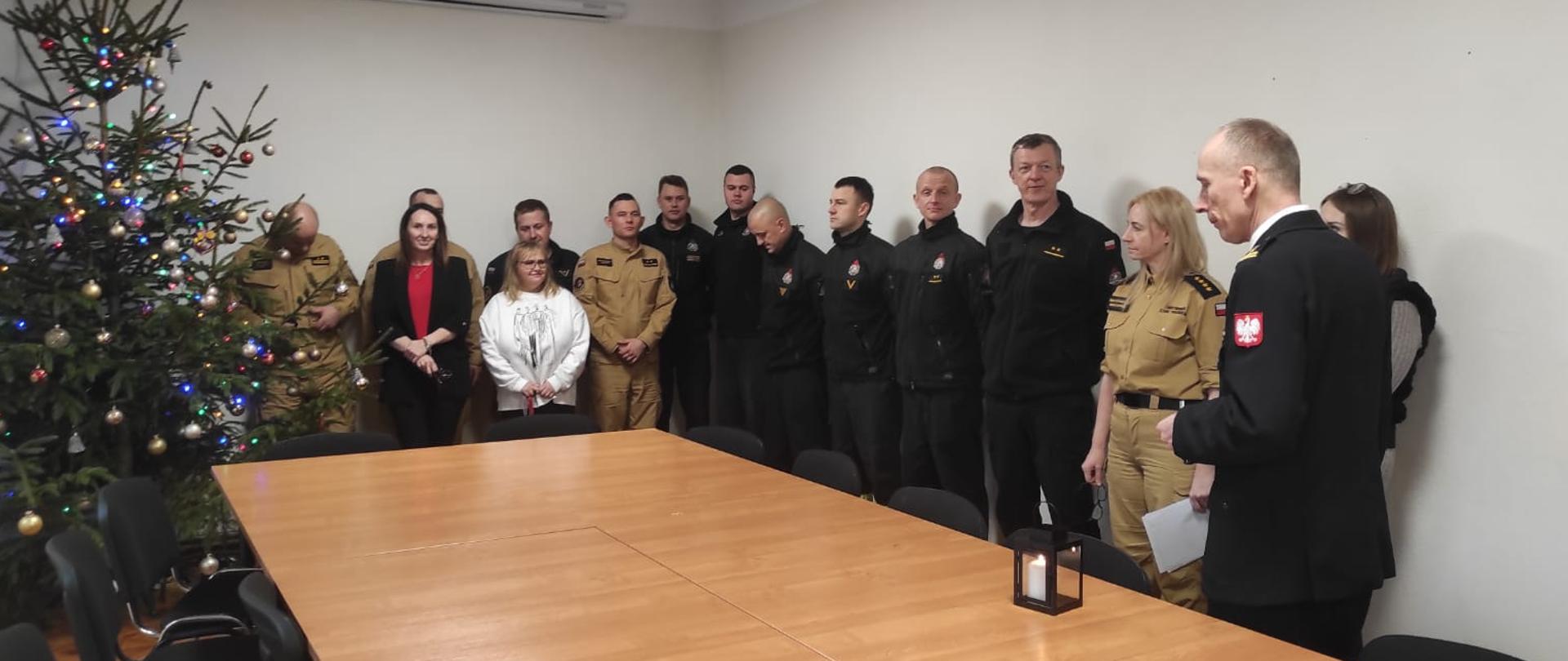 Zdjęcie przedstawia wręczenie nagrody w świetlicy komendy psp w świdwinie, komendant wręcza nagrodę strażakowi przy załodze