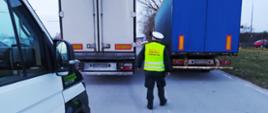 Ciężarówki skontrolowane przez inspektorów kujawsko-pomorskiej ITD. W centrum dwa pojazdy ciężarowe. Za nimi stoi inspektor ITD. Po lewej furgon ITD.