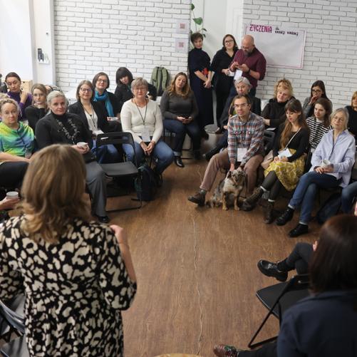 Ludzie siedzą w półokręgu i słuchają przemówienia