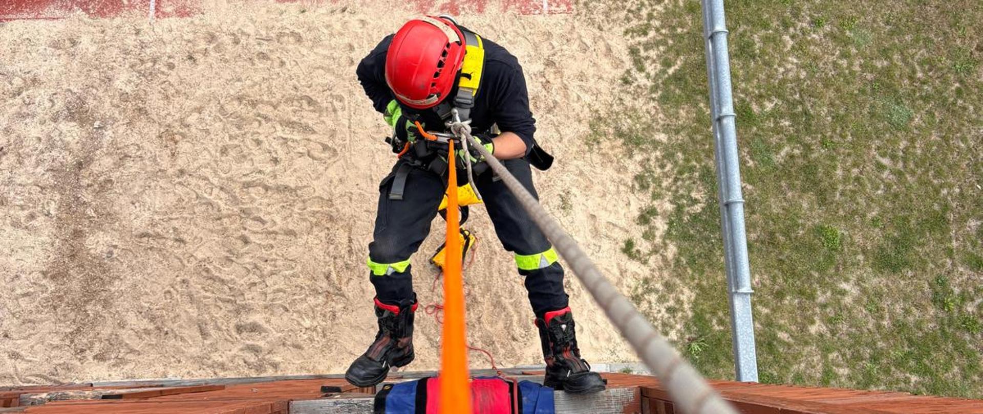 Strażak na wysokości zabezpieczony liną