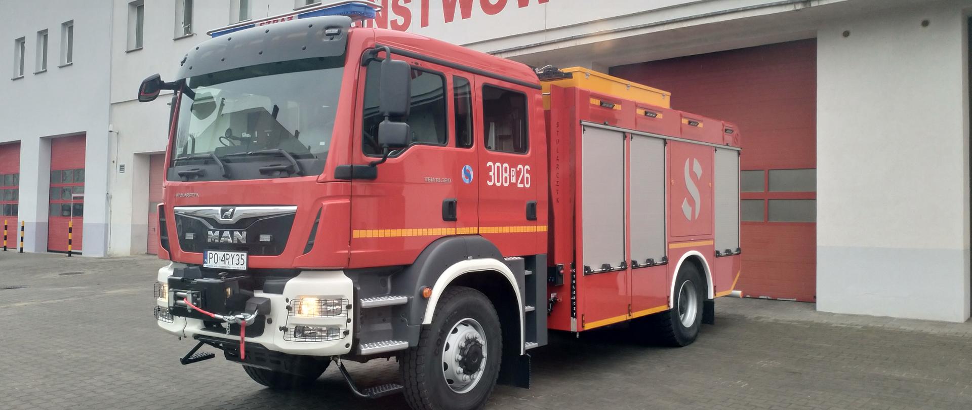 samochód ratowniczo gaśniczy w kolorze czerwonym , w tle bramy garażowe