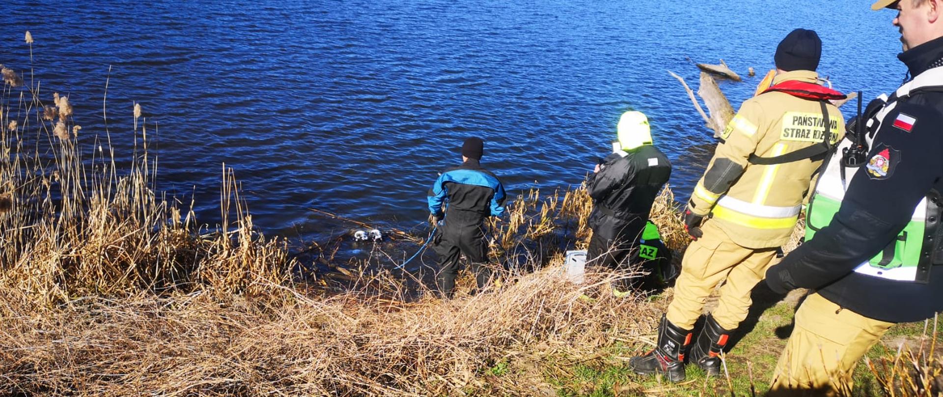 Na zdjęciu widnieją strażacy w trakcie prowadzonych działań na akwenie wodnym, związanymi z poszukiwaniem osoby zaginionej. 