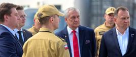 Na zdjęciu widać KP PSP w Zgierzu oprowadzającego gości - Wiceministra SWIA Wiesława Szczepańskiego wraz z Senatorem RP – Marcinem Karpińskim oraz Wicestarostą Powiatu Zgierskiego – Sebastianem Duninem po terenie jednostki , w tle kontenery OLiOC