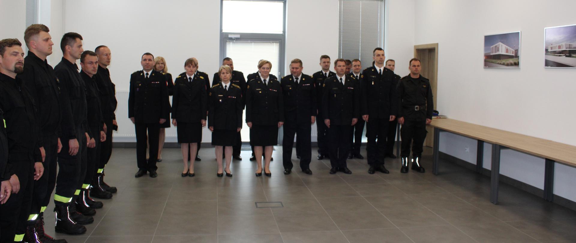 Zdjęcie przedstawia funkcjonariuszy codziennych i zmianowych na świetlicy Jednostki Ratowniczo-Gaśniczej Nr 3 w Rzeszowie ustawionych w dwuszeregu. Funkcjonariusze w umundurowaniu koszarowym oraz wyjściowym stoją w postawie zasadniczej.