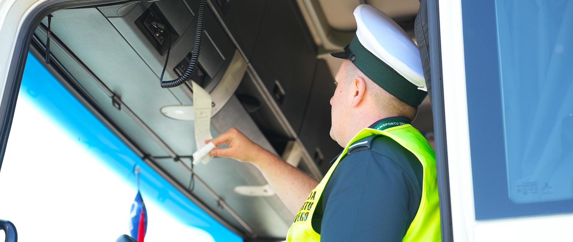 Inspektor trzyma w dłoni wydruk z tachografu