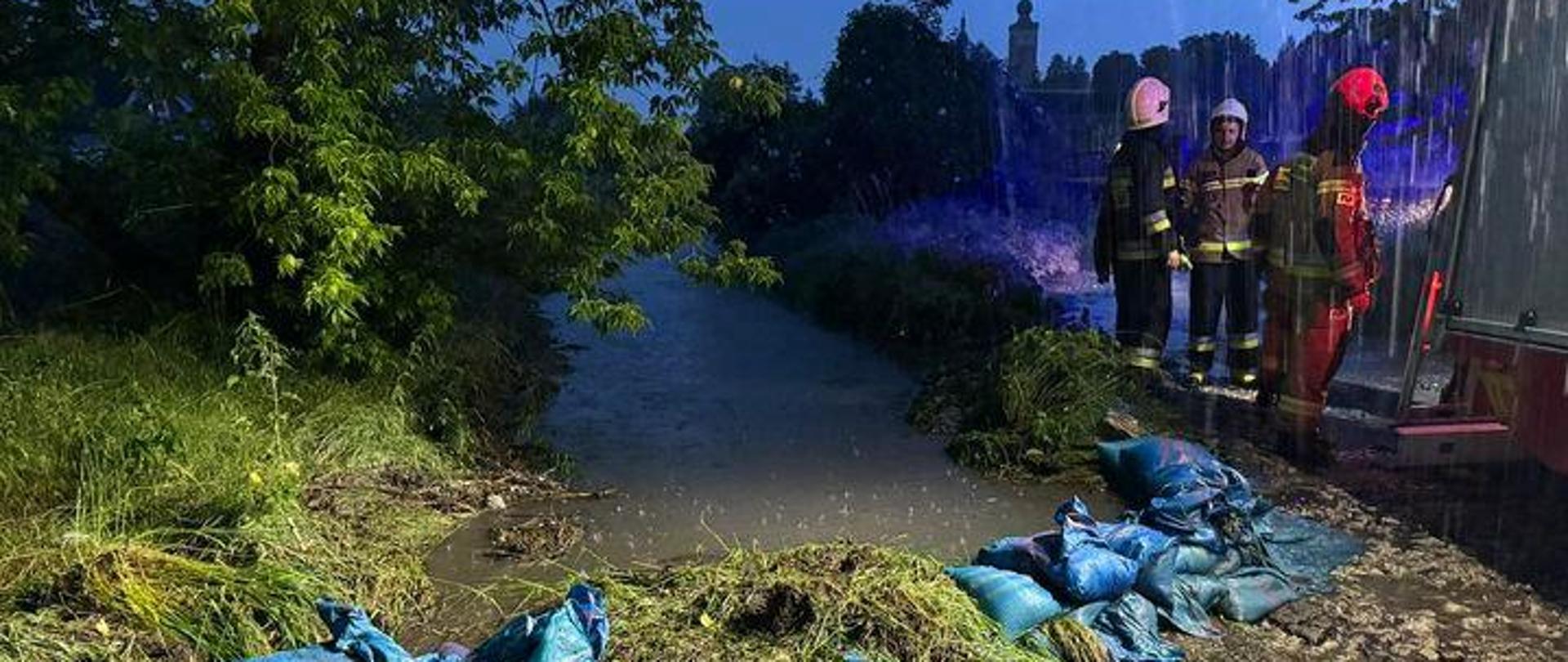 Na zdjęciu widoczny strażacy oraz zatamowany przepust 