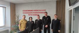 Zdjęcie przedstawia funkcjonariuszy Państwowej Straży Pożarnej w Zgierzu na tle napisu Stanowisko Kierowania Komendanta Powiatowego PSP w Zgierzu 