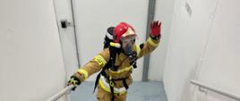 Strażak podczas biegu po schodach. Strażak mija 23 piętro budynku. Ubrany jest w umundurowanie specjalne oraz sprzęt ochrony układu oddechowego.