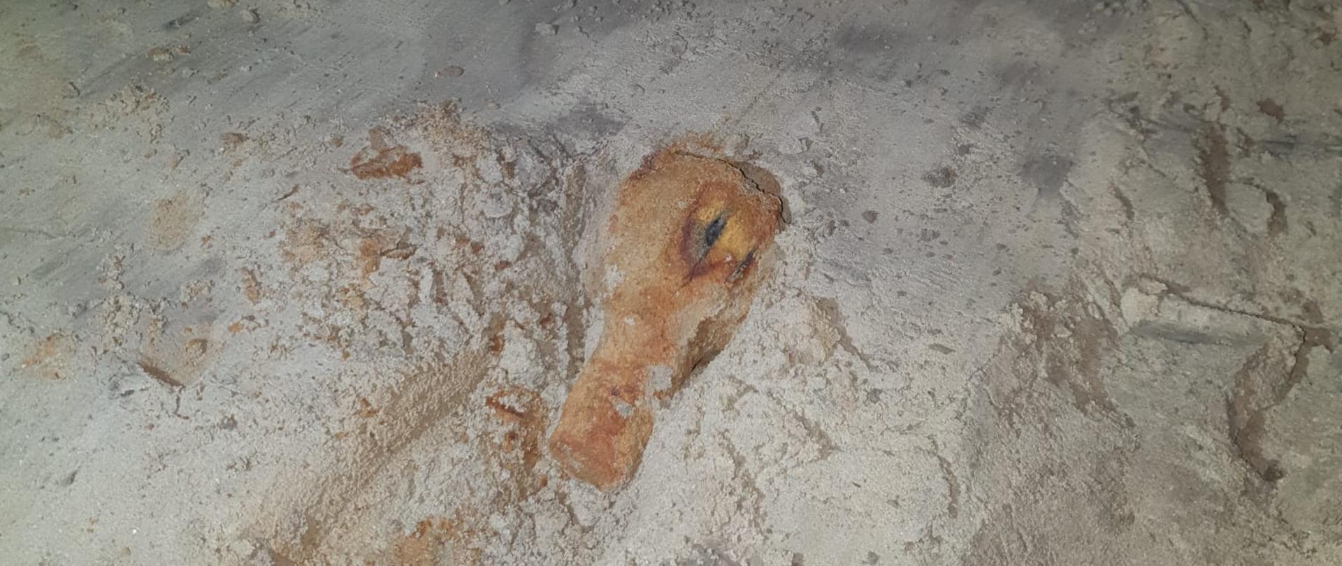 Na pisaku leży zardzewiały pocisk.