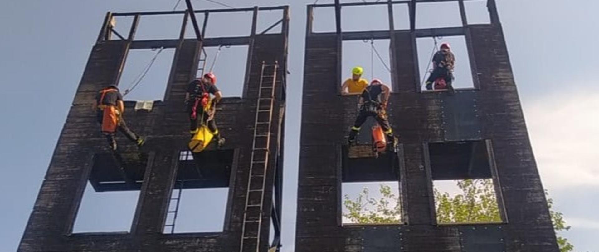trzech ratowników wysokościowych w trakcie ćwiczeń na wspinalni