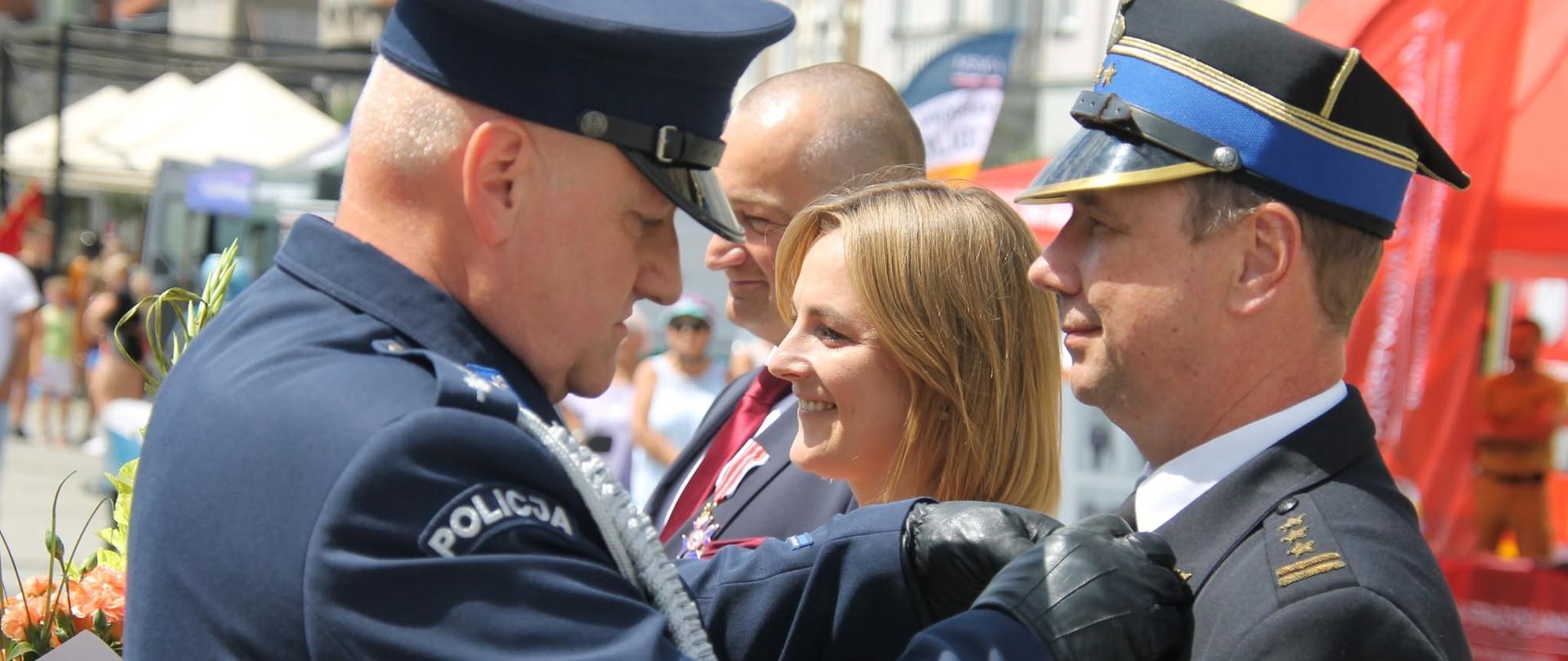 Zdjęcie przedstawia Komendanta Policji wręczającego odznaczenie Komendantowi Państwowej Straży Pożarnej.