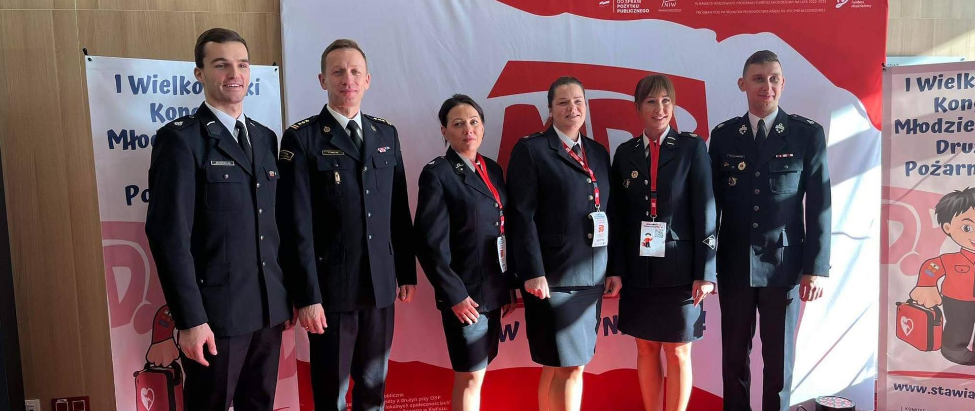 Z-ca Komendanta Wojewódzkiego, druhny i druhowie na tle baneru MDP