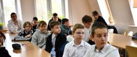 Uczestnicy konkursu - młodzież, siedząca przy stole, czekając na egzamin.