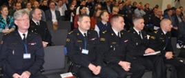 konfernecja, w dużej sali w pierwsyzm rzędzie siedzą strażacy, w kolejnych rzędach inni słuchacze