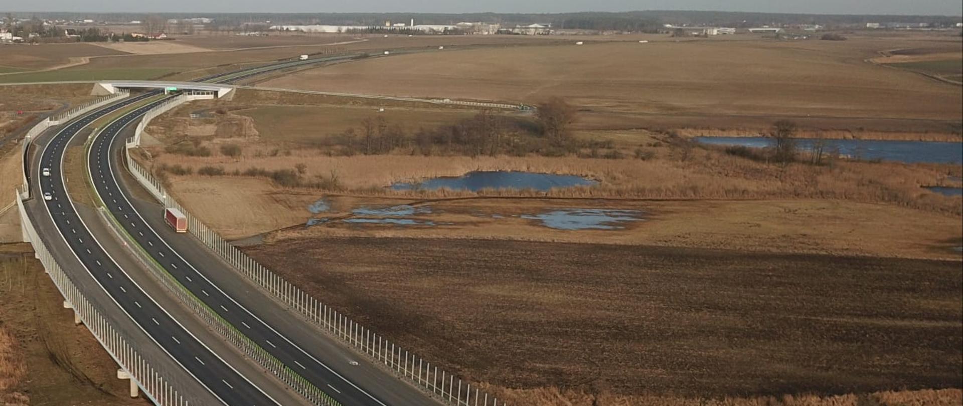 Dwie jezdnie drogi ekspresowej przecinające łąki - obok drogi oczka wodne 