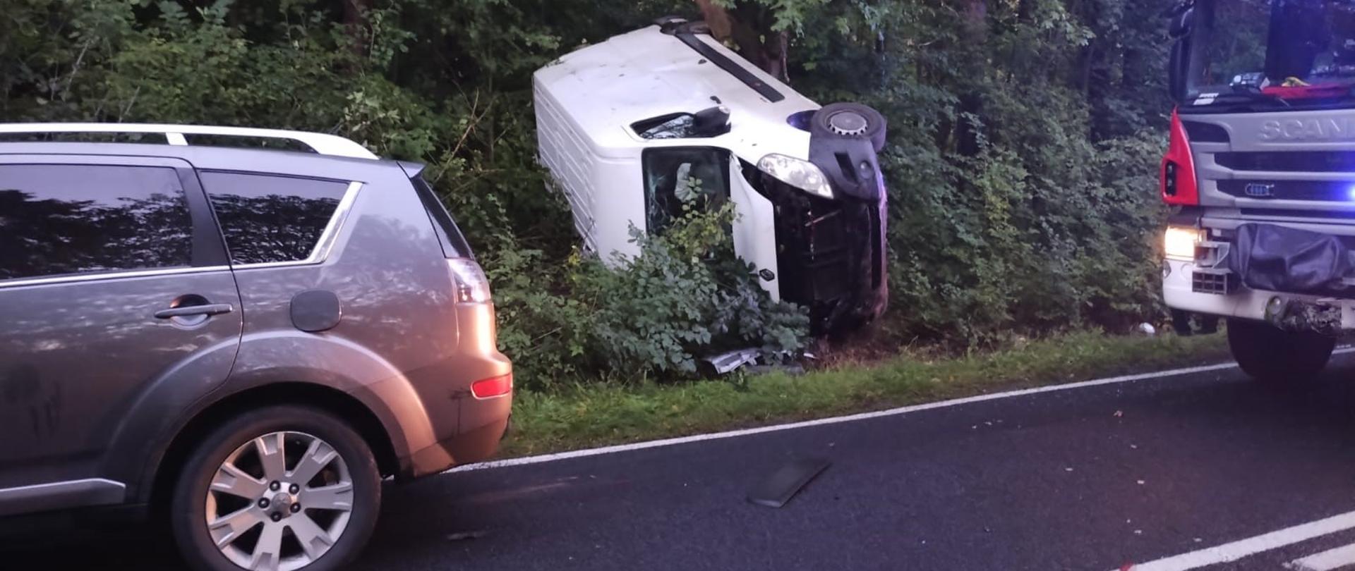 Zdjęcie przedstawia samochód przewrócony na bok po wypadku.
