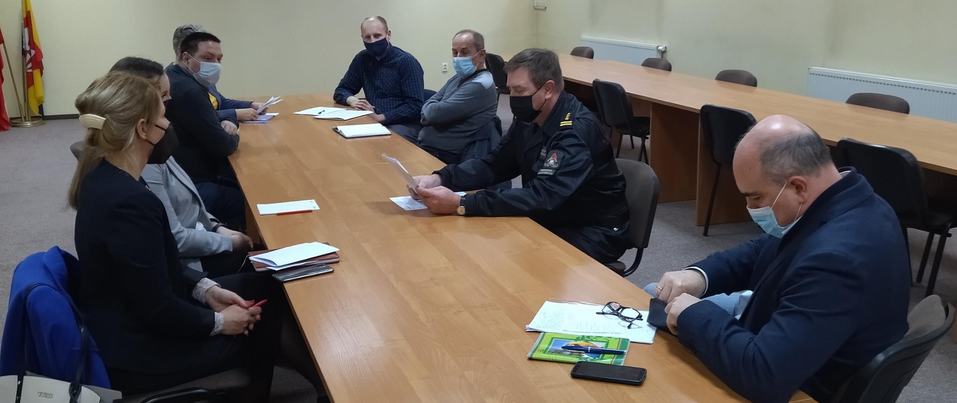 Przy stole siedzą przedstawiciele władz powiatowych i gminnych oraz komendant powiatowy PSP w Grodzisku Mazowieckim omawiający sprawy przygotowania samorządów oraz jednostek krajowego systemu ratowniczo-gaśniczego do działań w okresie zimowym 2021/2022.