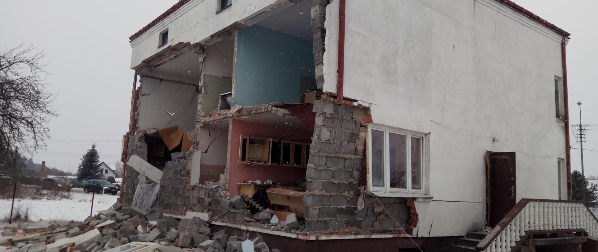 Wybuch gazu Olszewnica Nowa. Na zdjęciu budynek mieszkalny. Zalaona jedna ściana całkowicie widać pomieszczenia w środku. Kolejna ściana popękana. PRzed domem leżą cegły z zawalonej ściany.