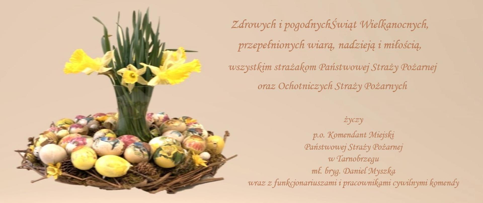 Grafika przedstawia świąteczne motywy, tj. wiosenne kwiaty i pisanki oraz życzenia.