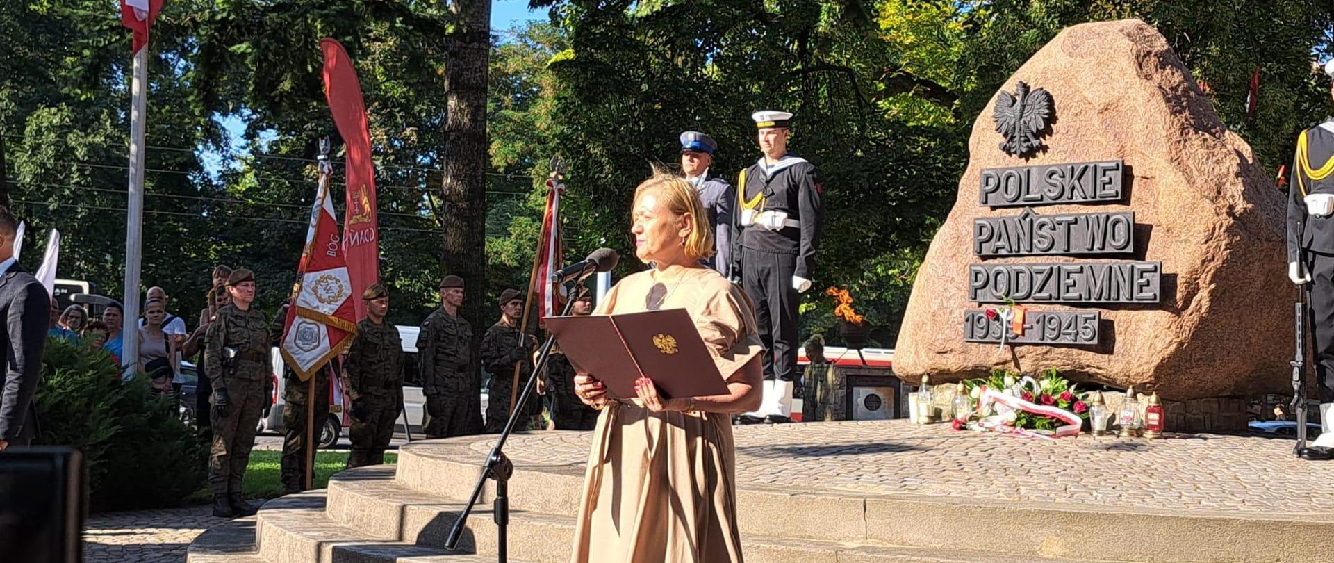 kobieta (wojewoda) stoi przed pomnikiem Polskiego Państwa Podziemnego i przemawia