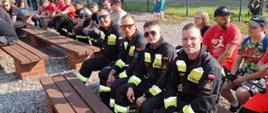 Czterech strażaków siedzących na ławce i czekających na rozpoczęcie mistrzostw.