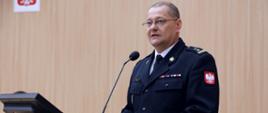 Nowy Zastępca Komendanta Centralnej Szkoły PSP przemawia do mikrofonu stojąc na mównicy