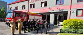 Poczet flagowy podczas podnoszenia Flagi Rzeczpospolitej Polskiej na maszt. w tle strażacy w szyku