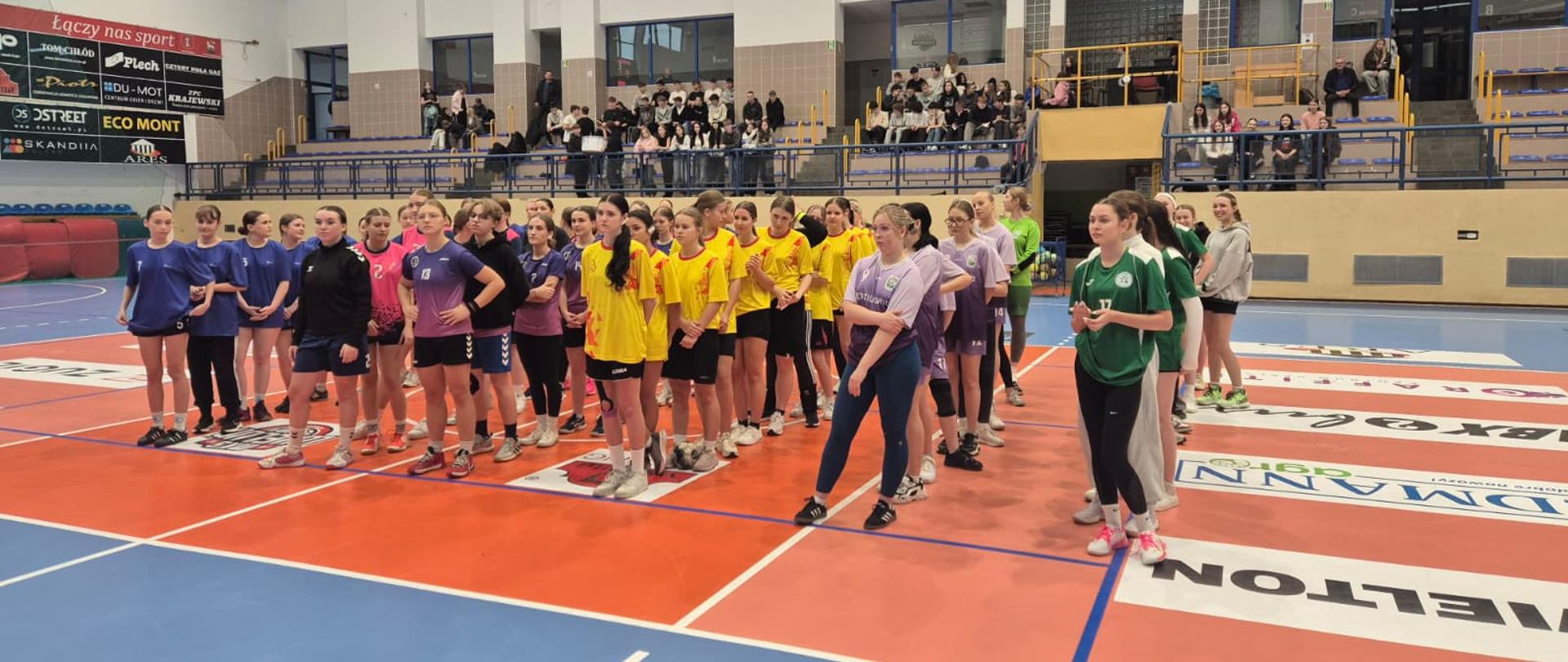 Drużyny stojące w rzędzie na tle hali sportowej podczas otwarcia zawodów